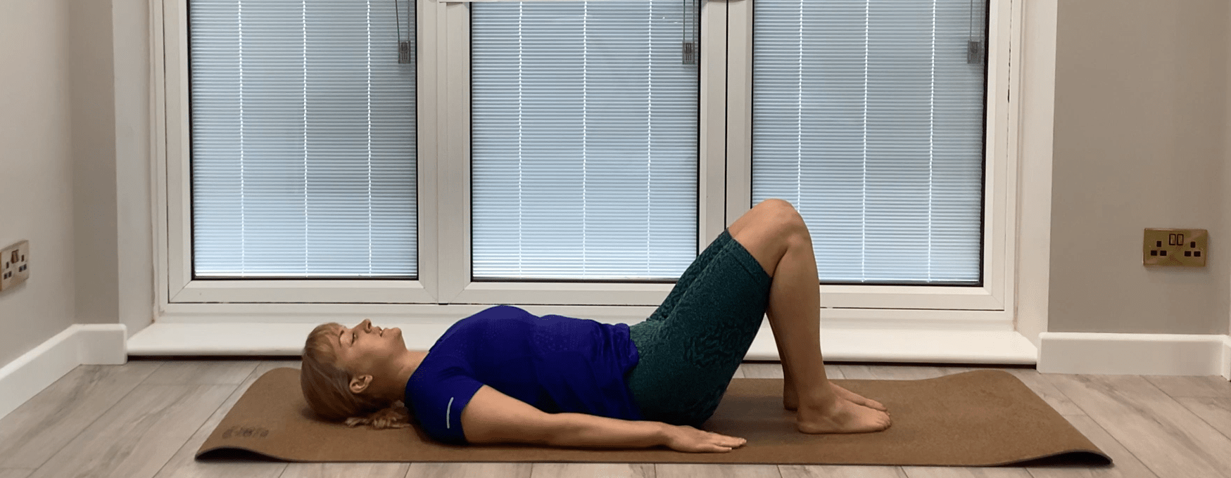 Image of the instructor for our post hernia surgery recovery exercise programme. She is laying on a mat on the floor.