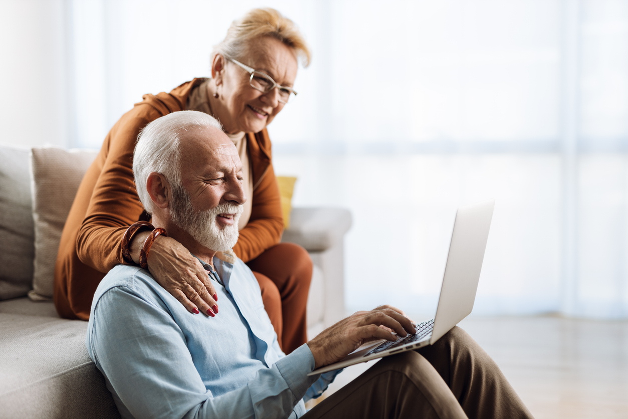A photo of an older couple sat together looking up medical insurance for hernia surgery on a laptop