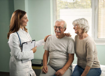 A female doctor in an exam room explaining what a hernia is to a male patient and his wife, explaining