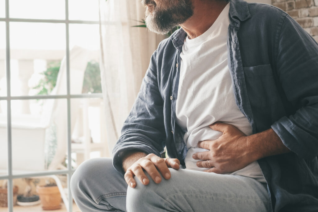 A man holding his abdomen, experiencing symptoms because he had to delay hernia surgery.